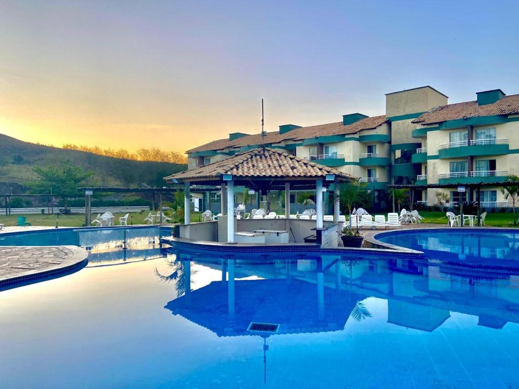 a swimming pool with a gazebo in front of a hotel at Apartamento Aldeia das Águas l Condomínio Village das Águas in Barra do Piraí