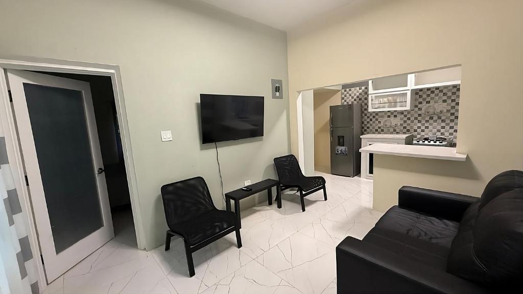 a living room with a couch and chairs and a kitchen at The cozy spot negril in Negril