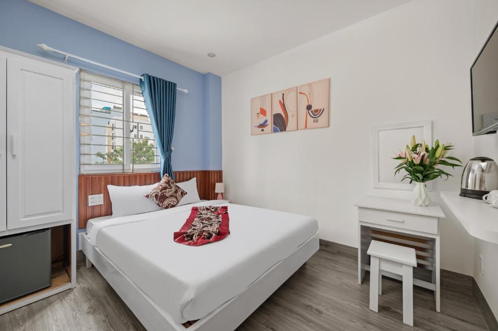 una camera da letto con un grande letto bianco e una scrivania di Bao Chau Hotel a Da Nang