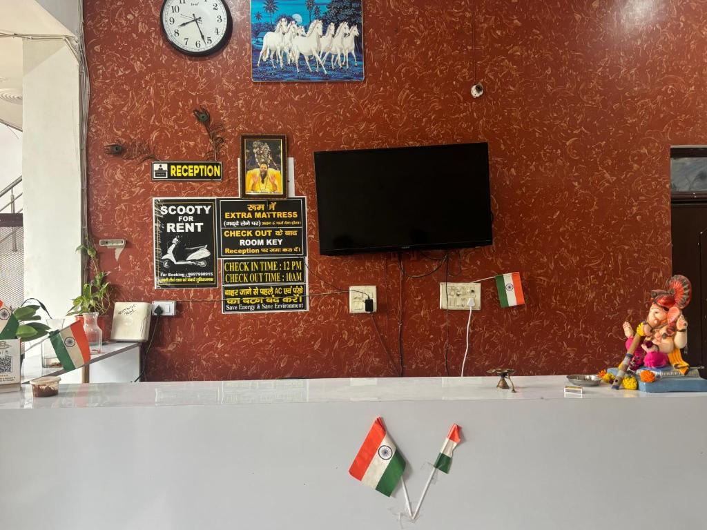 uma sala de estar com televisão e uma parede vermelha em Hari Dham em Vrindāvan