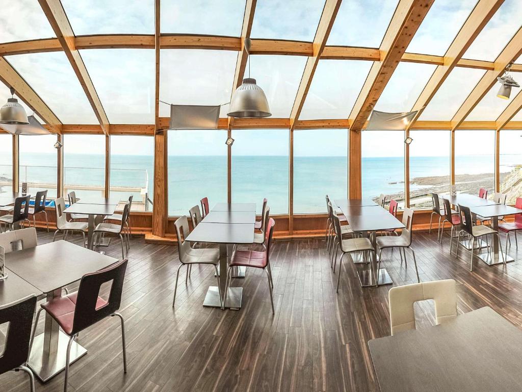 a restaurant with tables and chairs and a view of the ocean at Mercure Granville Le Grand Large in Granville