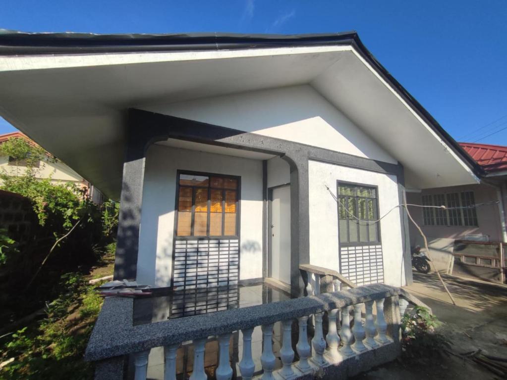 a small white house with a porch and stained glass windows at Belle Go in Bauang