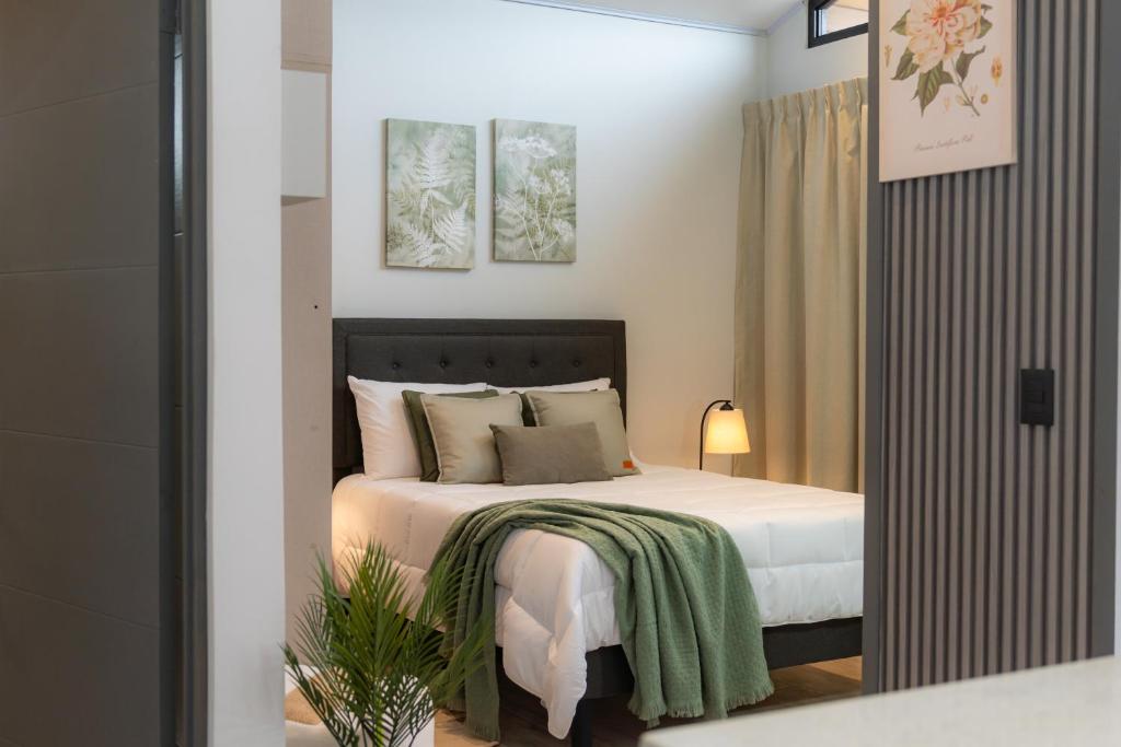 a bedroom with a bed with a green blanket on it at Sakura Haus in Turrialba