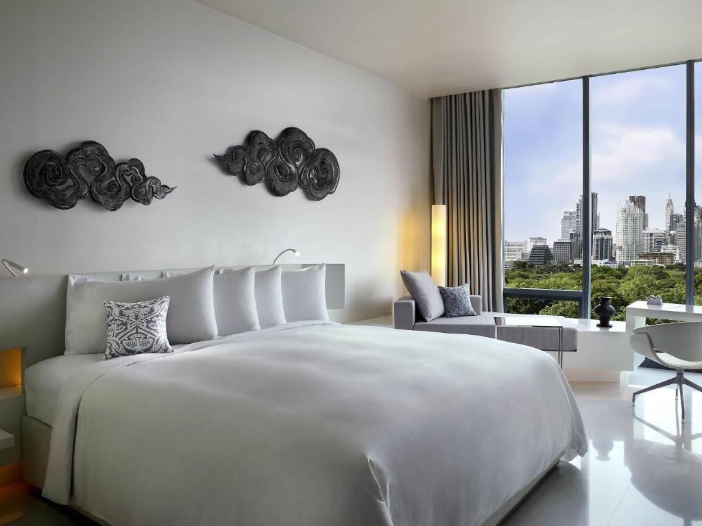 a white bedroom with a large bed and a large window at SO/ Bangkok in Bangkok