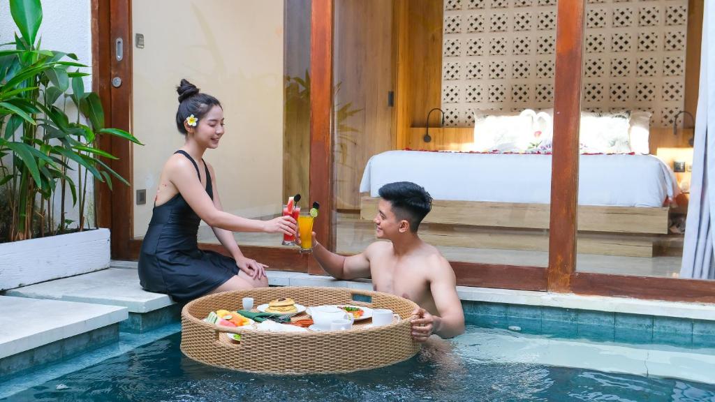 een vrouw naast een man in een zwembad bij Danka Villa Sanur in Sanur