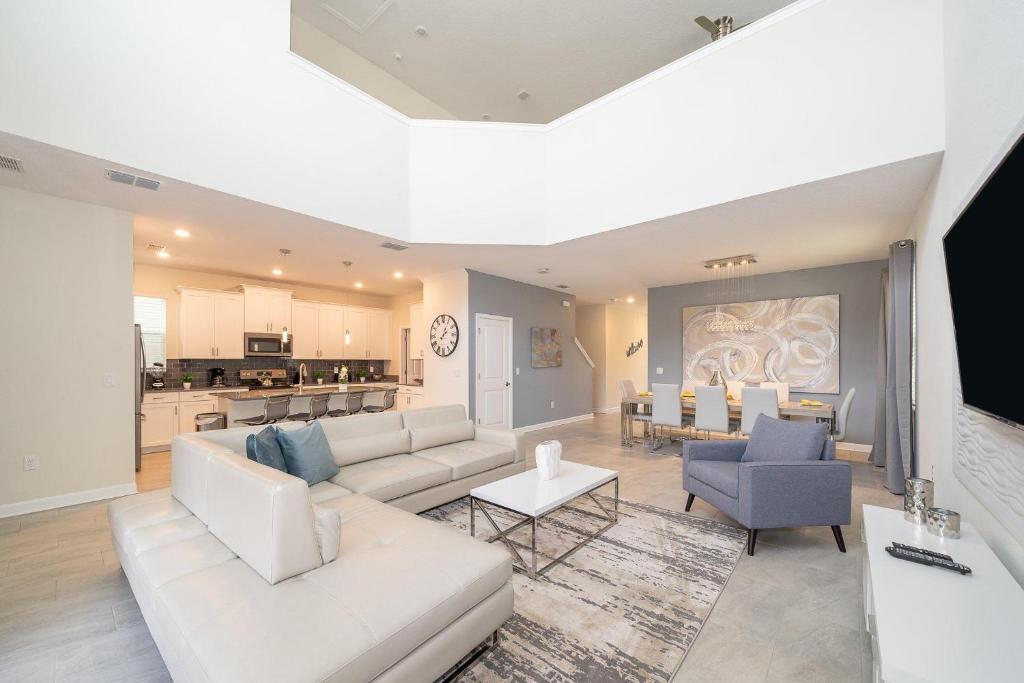 a living room with white furniture and a kitchen at 2744HM VILLA 5 BED/5 BA (SANITIZED) in Kissimmee