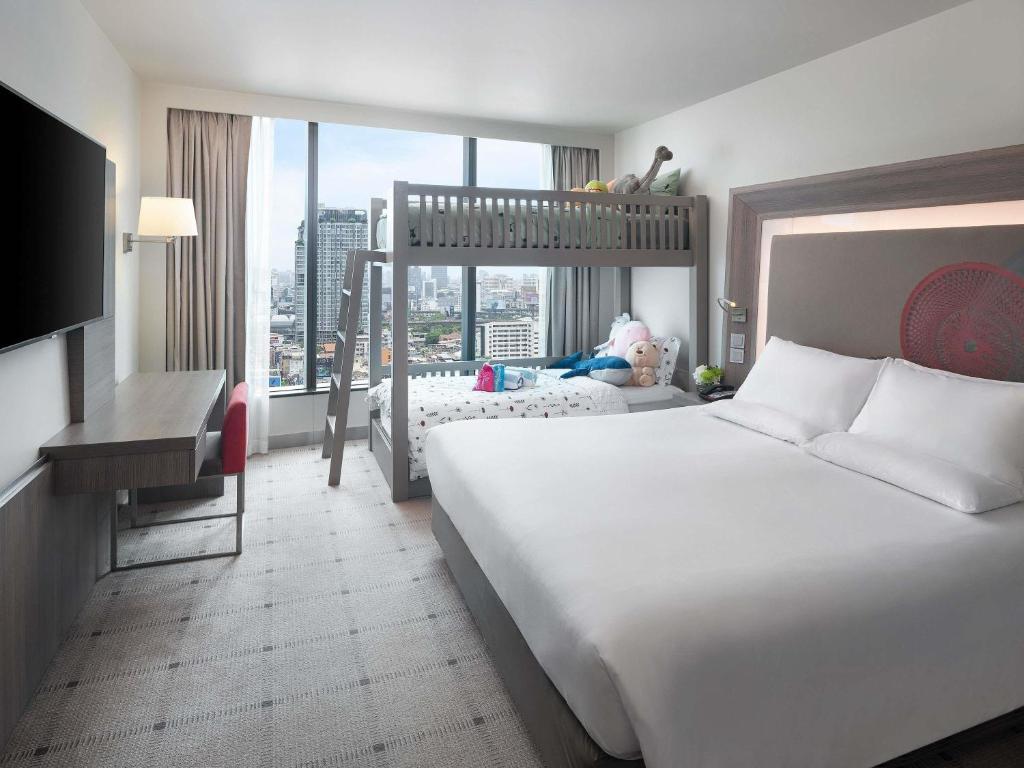a hotel room with a large bed and a large window at Novotel Bangkok Platinum Pratunam in Bangkok