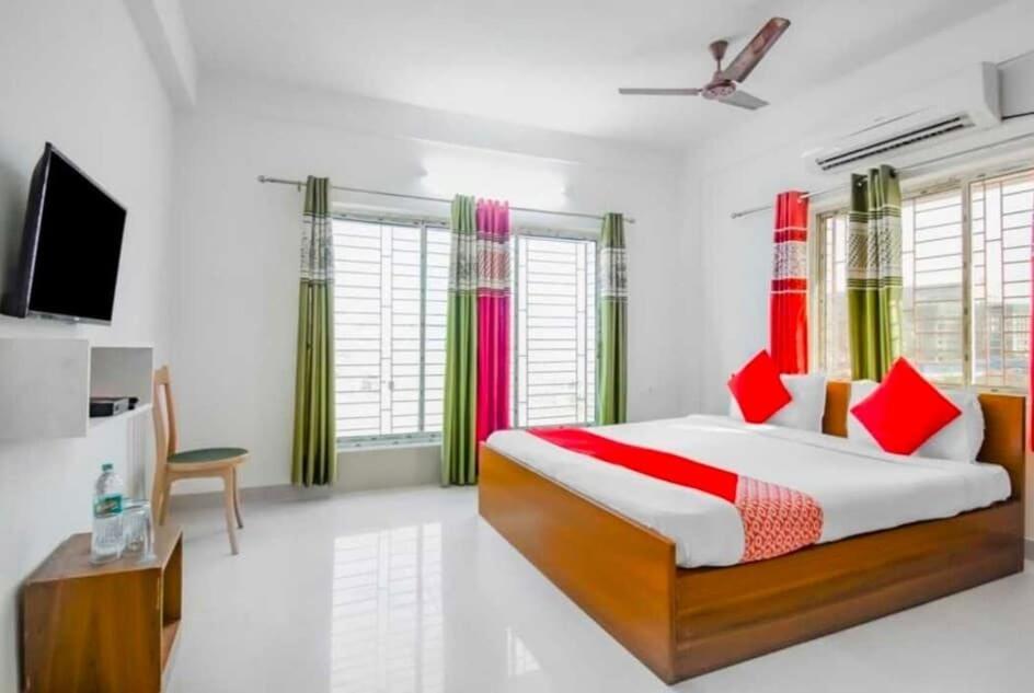 a bedroom with a large bed with red and green curtains at Hotel O Amar Raj Stay in Kolkata