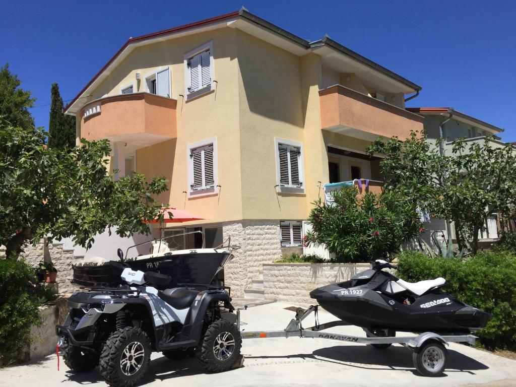 una moto e uno scooter parcheggiati di fronte a una casa di Apartments Prahović a Ždrelac