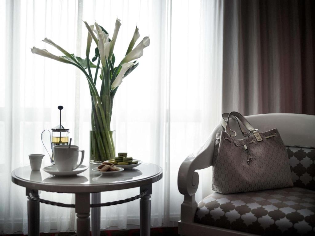 a table with a vase of flowers and a candle on it at Pullman Hanoi in Hanoi