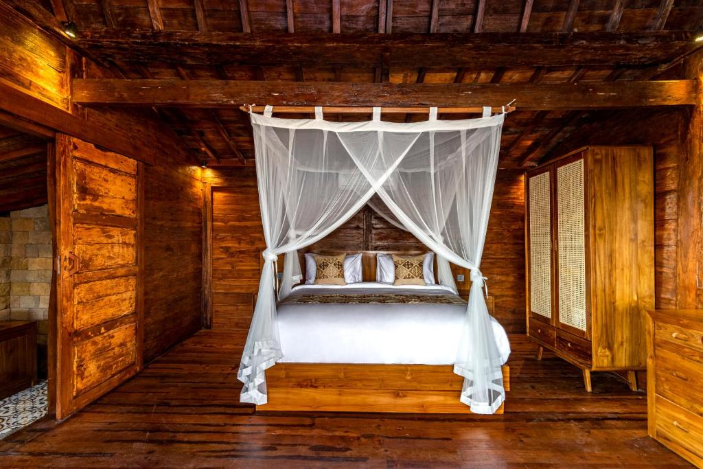 Dormitorio con cama con dosel en una cabaña en Kamania Villa Ubud by Dhananjaya Hospitality, en Tampaksiring