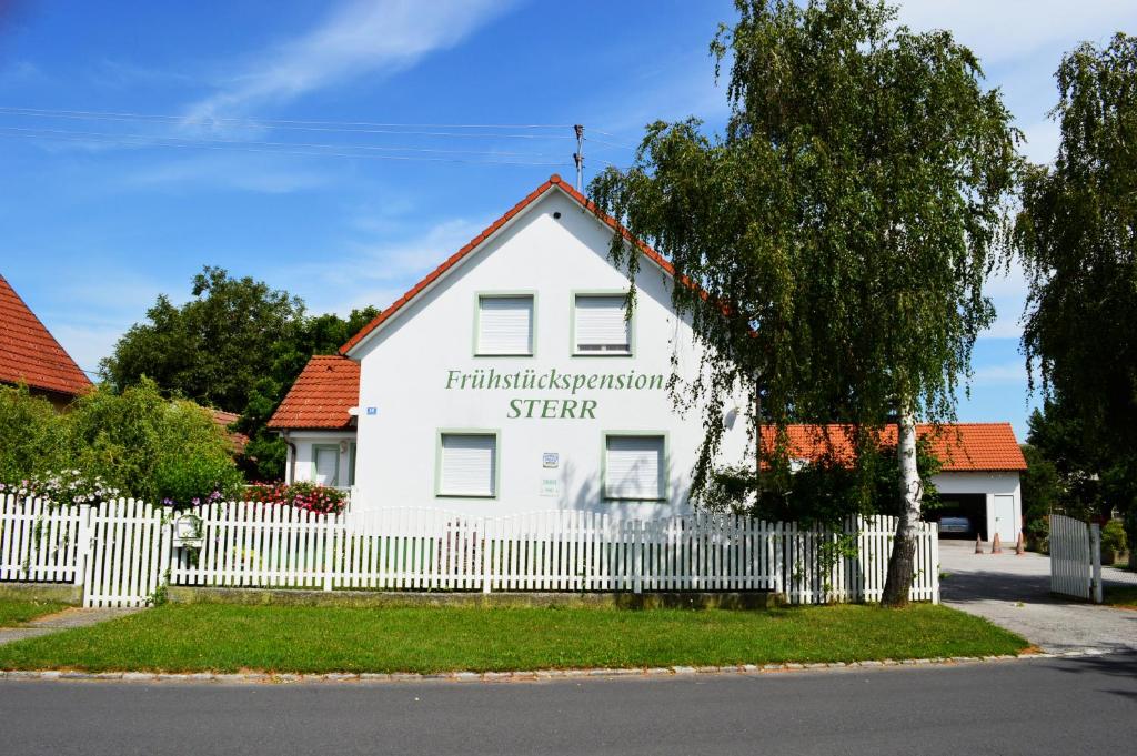 ein weißes Haus mit einem Zaun davor in der Unterkunft Frühstückspension Sterr in Strebersdorf
