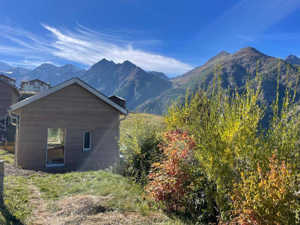 a small house on a hill with mountains in the background at Tiny Barrhorn in Grächen