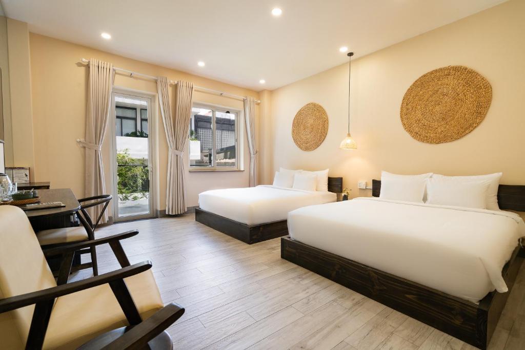 a hotel room with two beds and a desk at HemTouch House - Nguyễn Văn Mai in Ho Chi Minh City