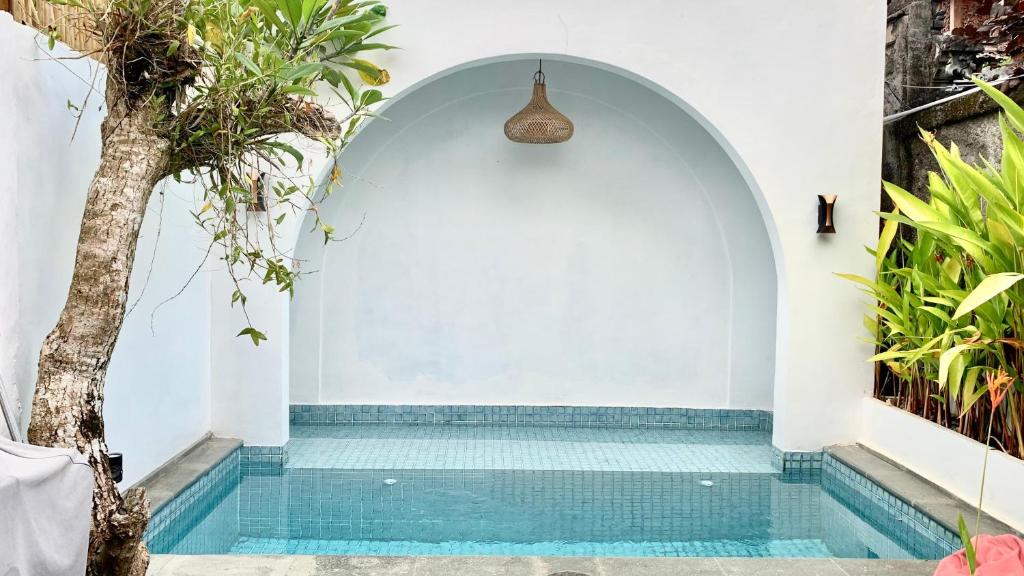 a swimming pool in a house with a white wall at Baliem Resort Jimbaran in Jimbaran