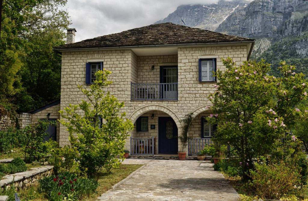 a stone house with a porch and mountains in the background at To Rodi in Papigko