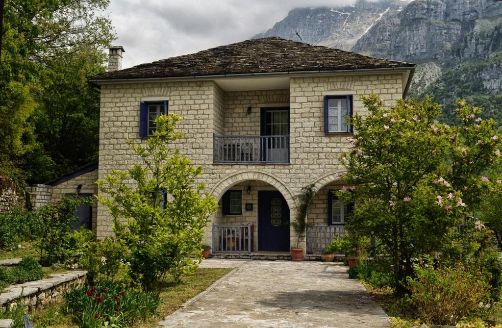 una casa de piedra con porche y montañas al fondo en To Rodi, en Papigko