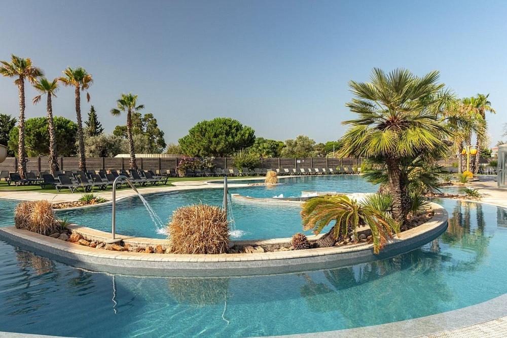 una piscina con palme in un resort di Mobil-home Ultimate 3Ch 6 pers Camping Les Dunes à TOREILLES a Torreilles