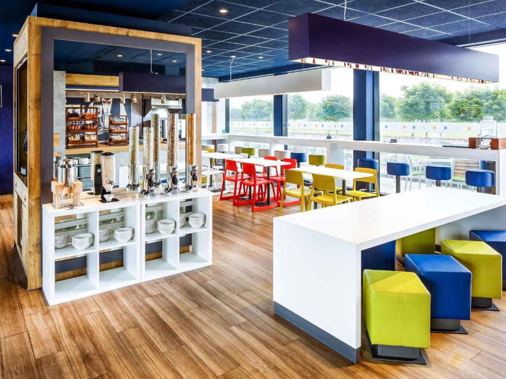 Un restaurante con sillas y mesas amarillas y azules. en ibis budget Hotel Edinburgh Park, en Edimburgo