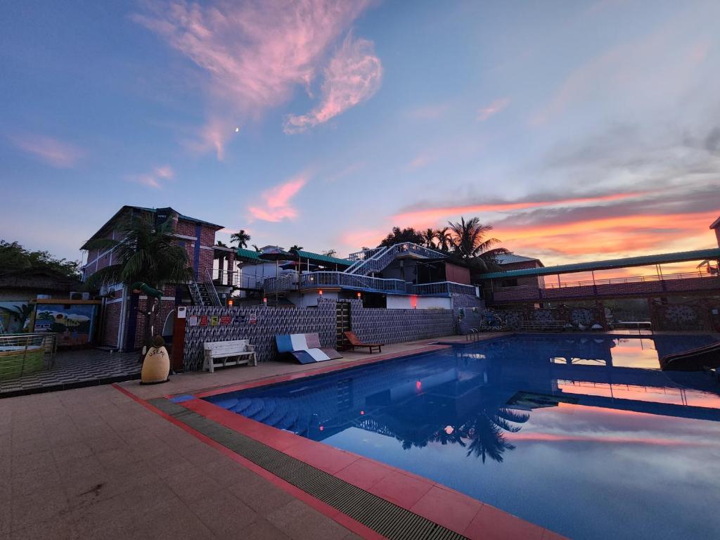 a swimming pool with a sunset in the background at Mukta Nagar Resort in Pitua