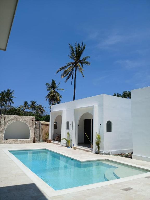 eine Villa mit einem Pool und einer Palme in der Unterkunft White Seeds Boutique Villas in Gili Trawangan