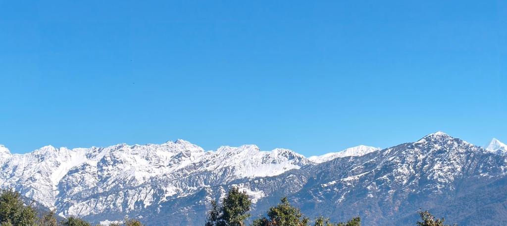 a snow covered mountain range with trees in the foreground at Top hill home stay in Sāma