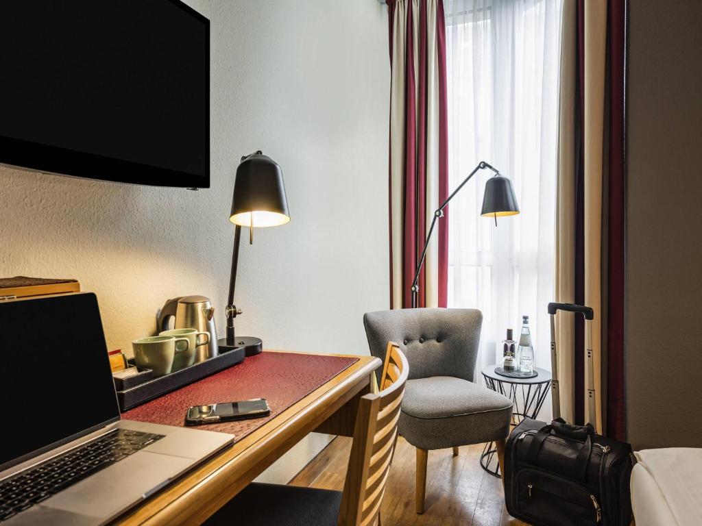 a hotel room with a desk with a laptop and a chair at Mercure Hotel Berlin Zentrum Superior in Berlin