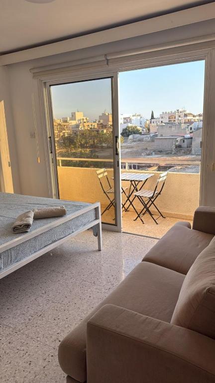 Una sala de estar con un sofá y una ventana grande. en Larnaca Ancient View Rooms, en Lárnaca