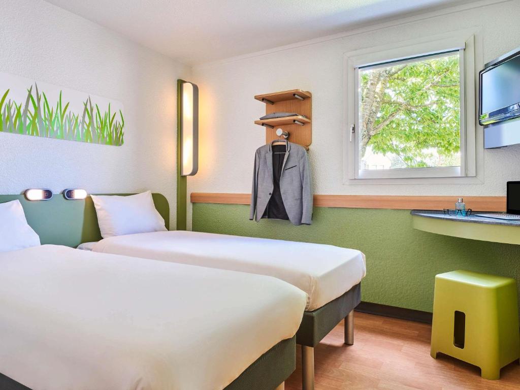 a hotel room with two beds and a sink at Ibis Budget Versailles Coignieres in Coignières
