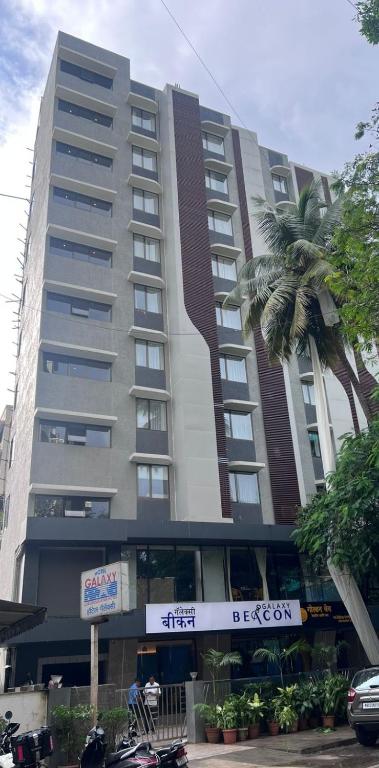 a tall building with a palm tree in front of it at Galaxy Beacon Hotel, Santacruz ,Mumbai in Mumbai