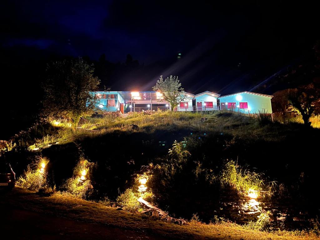 uma casa numa colina à noite com luzes em Almost Pahadi em Chopta