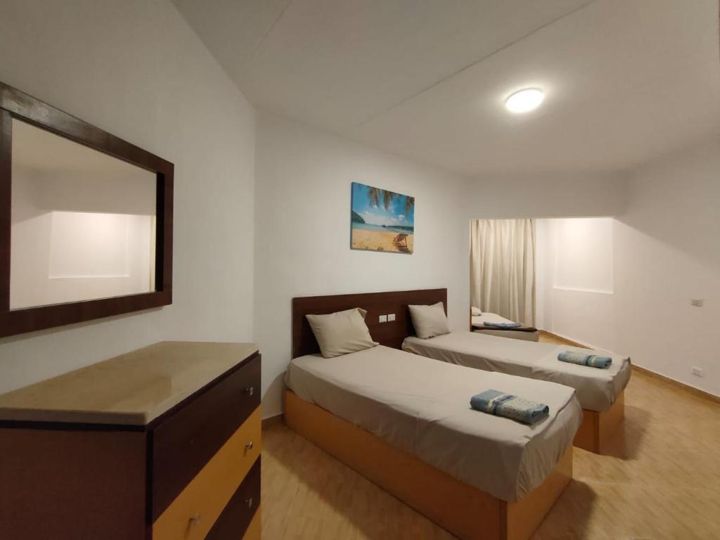 um quarto de hotel com duas camas e um espelho em Porto View Touristic Center em Hurghada