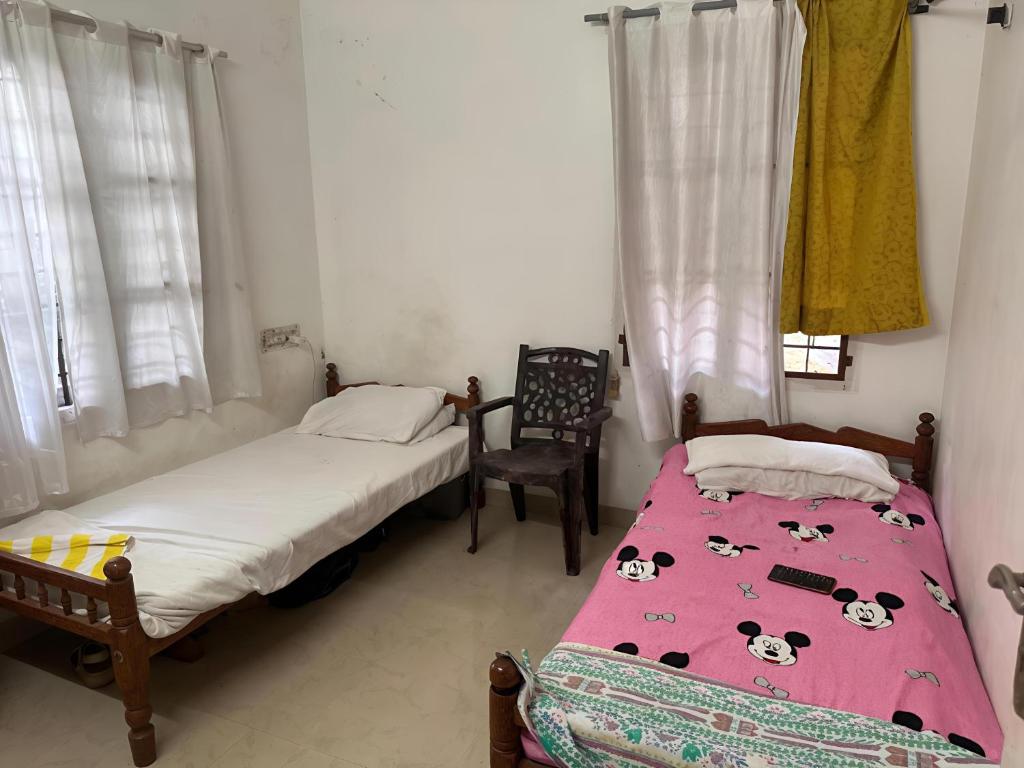 a bedroom with two beds and a chair at Honza Hostel in Cochin
