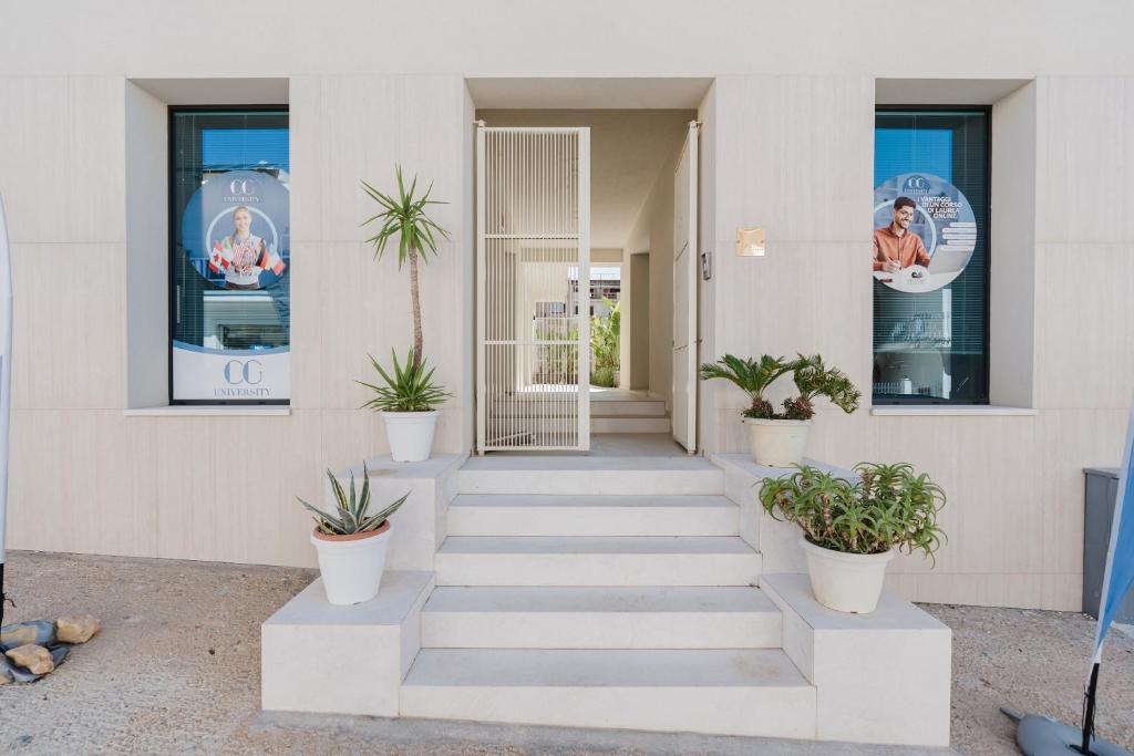 a white building with potted plants on the stairs at Gc Luxury Apartments e Spa in Santa Margherita di Belice