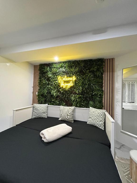 a bedroom with a black bed with a green wall at Jungle house,Arr autonome,Proche Aéroport & Gare in Beauvais