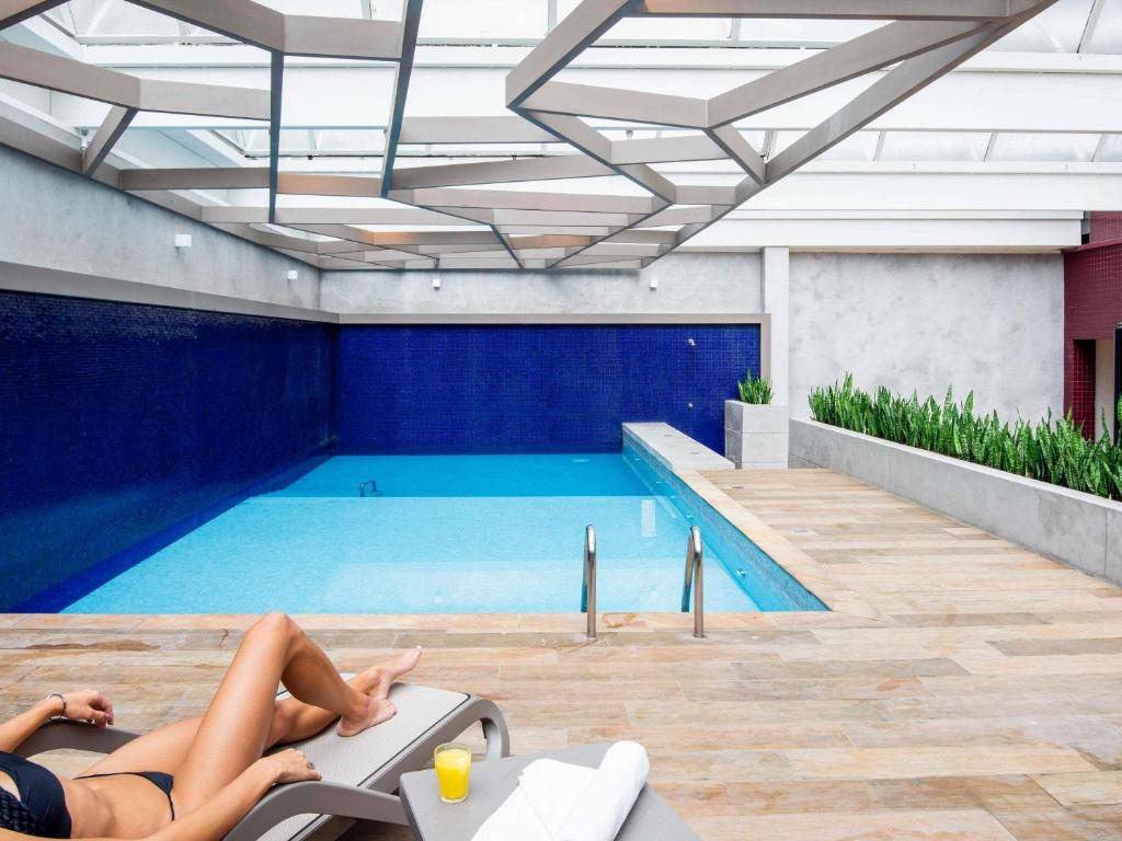 dos mujeres tumbadas en sillas en una piscina en Mercure Curitiba Batel, en Curitiba