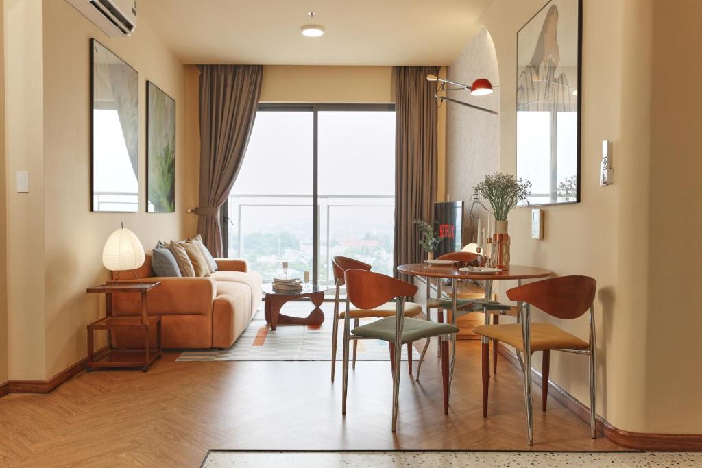 a living room with a couch and a table and chairs at HongHome Compass One in Ga Phú Văn