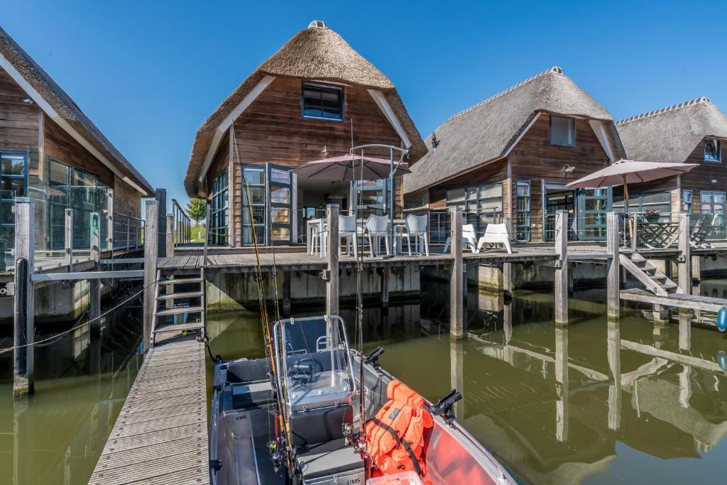 a boat is docked in front of a dock at Nautic Rentals - Watervilla's Zuiderhoeve in De Heen