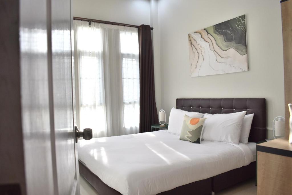 a bedroom with a bed with white sheets and a window at Khwanlom House in Lampang