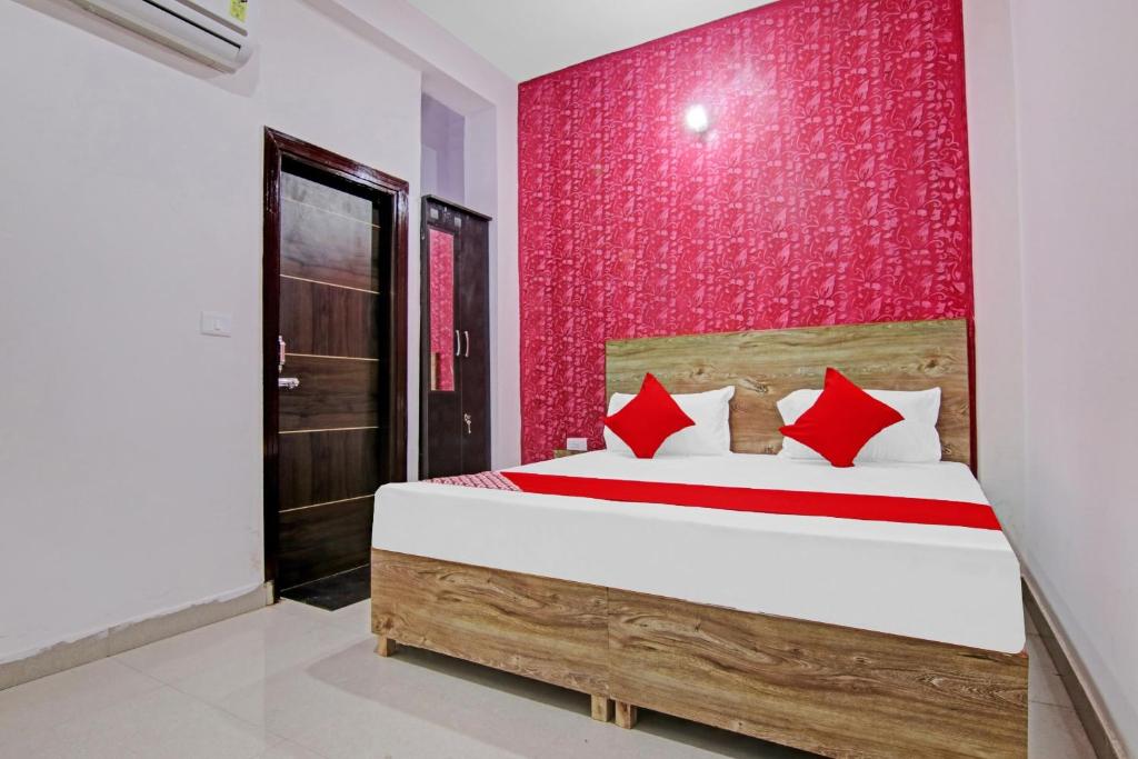 um quarto com uma cama e uma parede vermelha em Hotel O Suncity em Faridabad