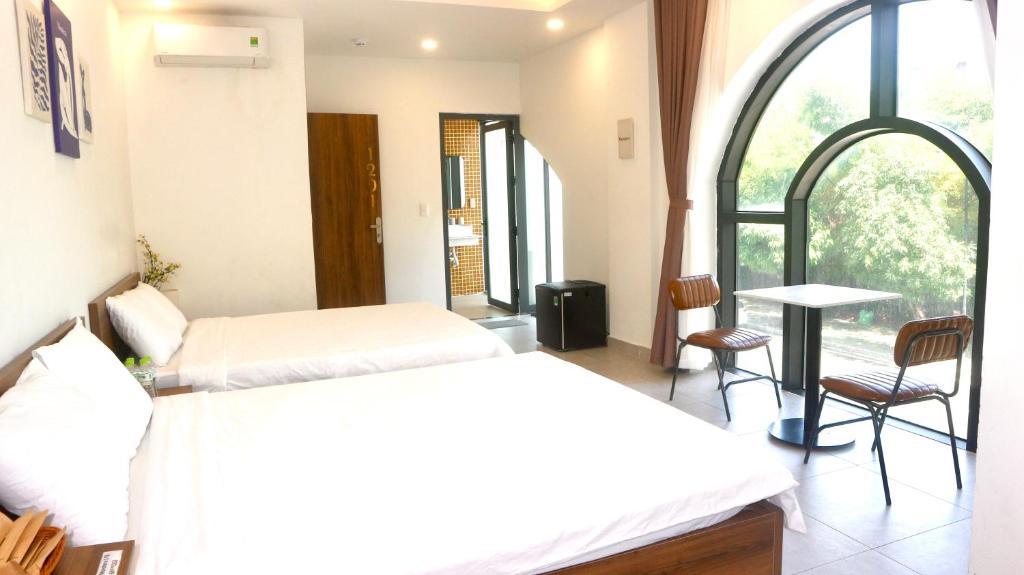 a room with two beds and a table and a window at Monstera Hotel and Coffee in Phú Quốc