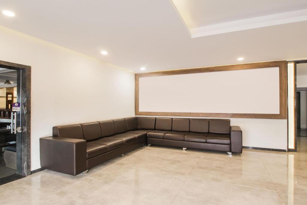 a brown couch in a room with a large screen at Hotel O Meridian in Bijāpur