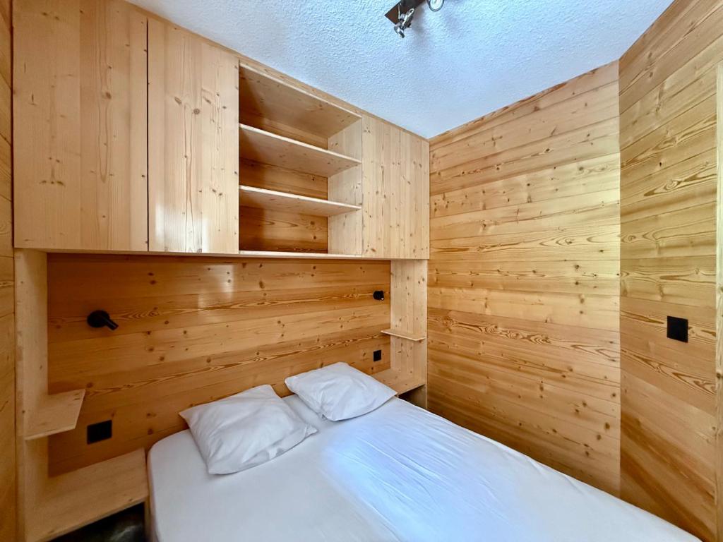 une chambre avec des murs en bois et un lit avec des oreillers blancs dans l'établissement Appartement au pied des pistes, à Châtel