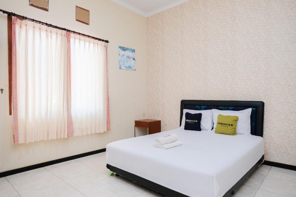 a bedroom with a white bed with yellow and black pillows at Urbanview Hotel Griya Surya Malang by RedDoorz in Malang