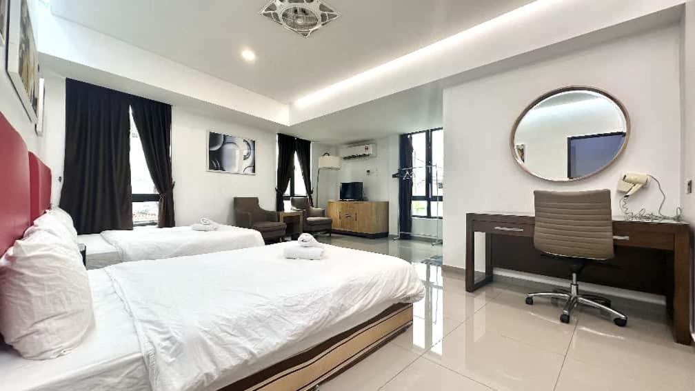 ein Schlafzimmer mit zwei Betten und einem Schreibtisch und einem Spiegel in der Unterkunft Jovial Boutique Hotel```` Kampung Baru in Bukit Mertajam