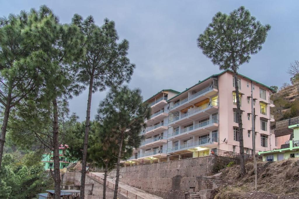 a building on the side of a hill with trees at The Western Heights I Serviced Apartments I Pvt Balcony I Lift I Peacefull Area I Family Accomodation I Kasauli By Exotic Stays in Kasauli