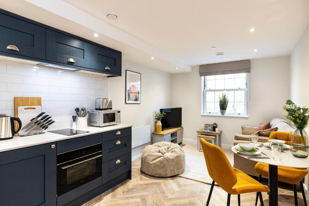 a kitchen with blue cabinets and a living room at Rock Mill 1 Bed Apartment 21 in Stony Middleton
