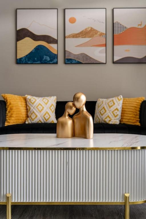 two bronze statues sitting on a table with a couch at Lux Haven Whitestown in Whitestown