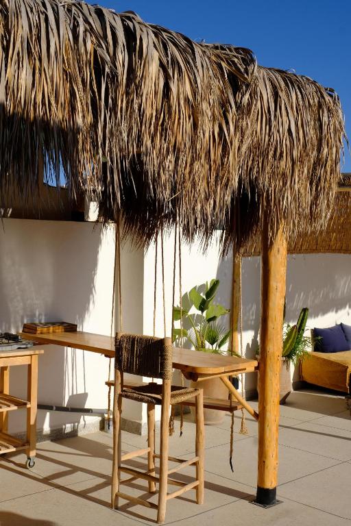 a table and a straw umbrella and a table and chair at Wavy Days Surf Lodge in Tamraght Ouzdar