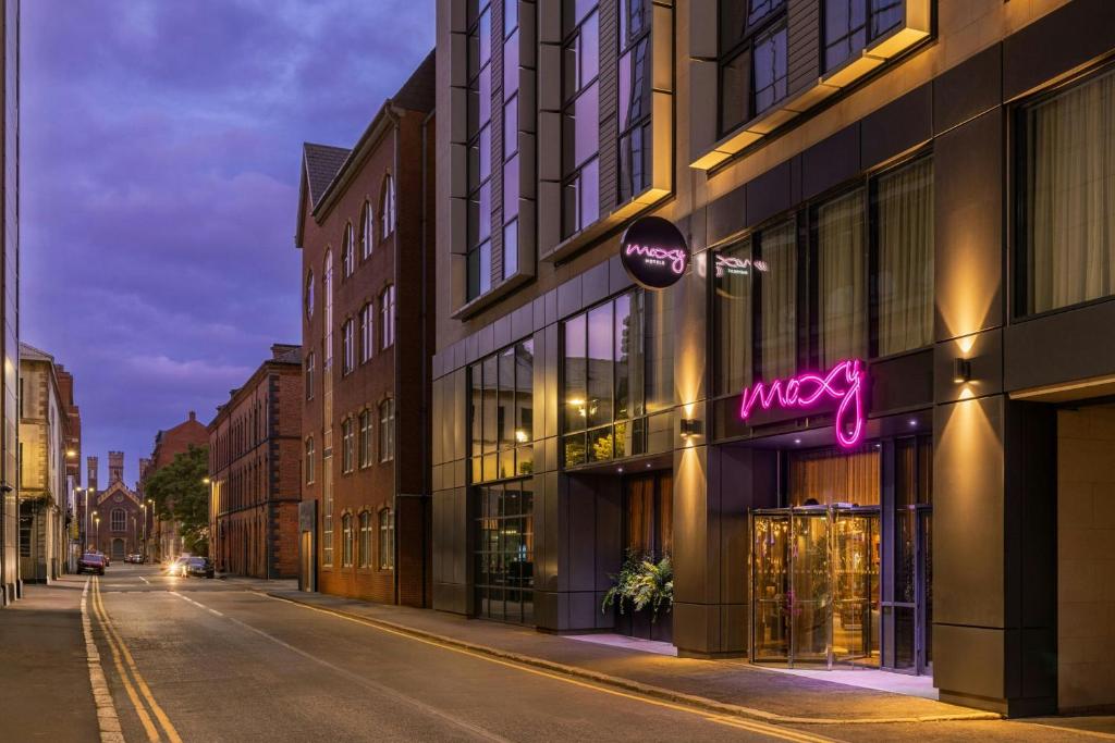 a city street at night with a store at Moxy Belfast City in Belfast